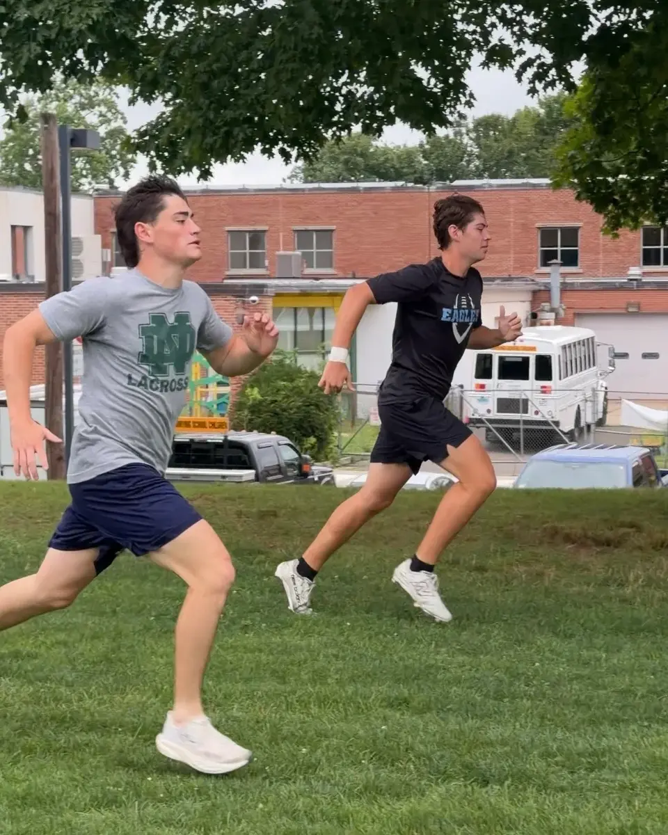 Two athletes sprinting during a coached session