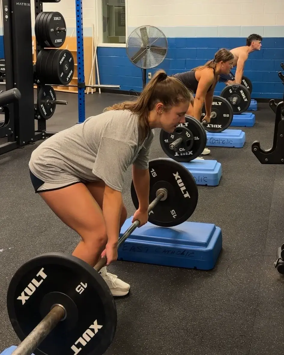 Three athletes beginning a coached strength exercise together